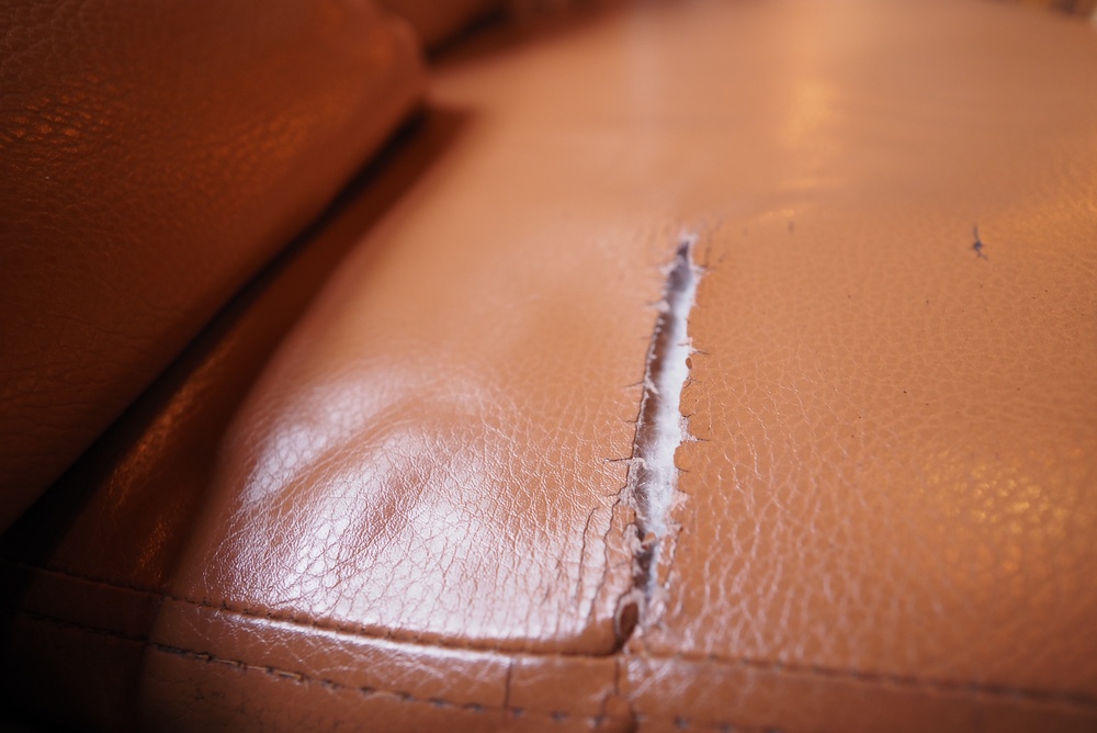 damaged leather sofa with a torn section in the upholstery