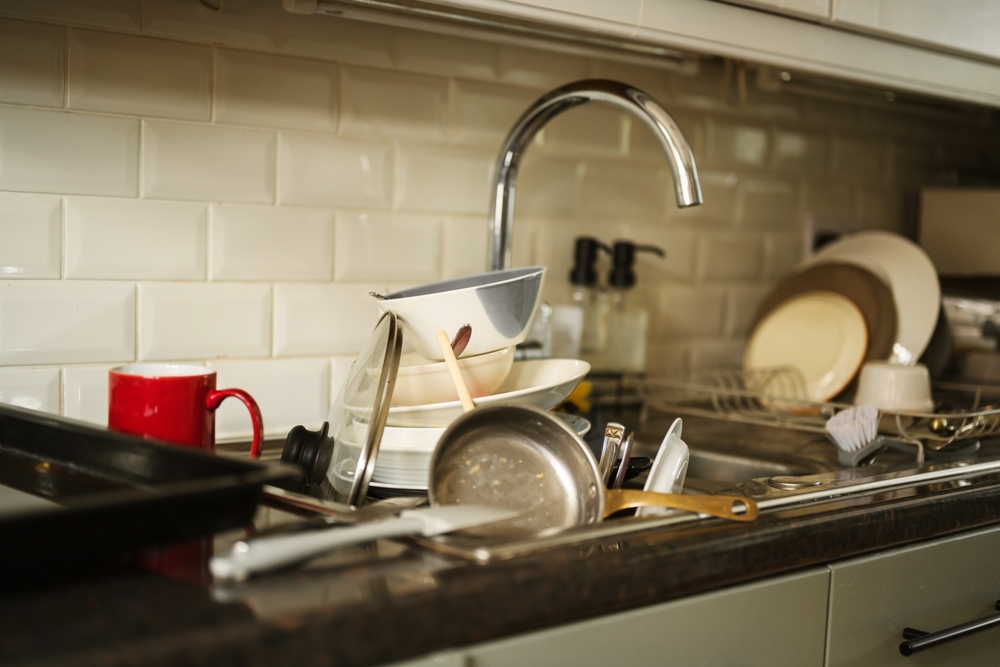 kitchen sink filled with unwashed dishes after a guest stay
